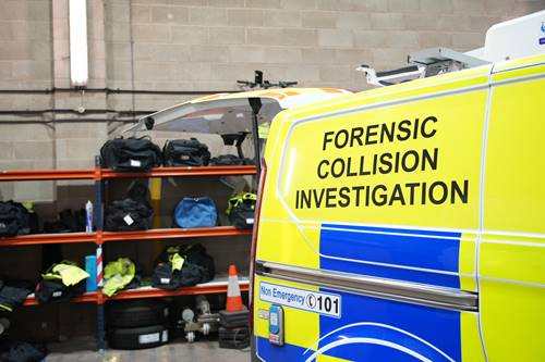 Photo of the back of the Forensic Collision Investigation Van. It is yellow with blue squares and has the text FORENSIC COLLISION INVESTIGATION on the side. The boot is open.